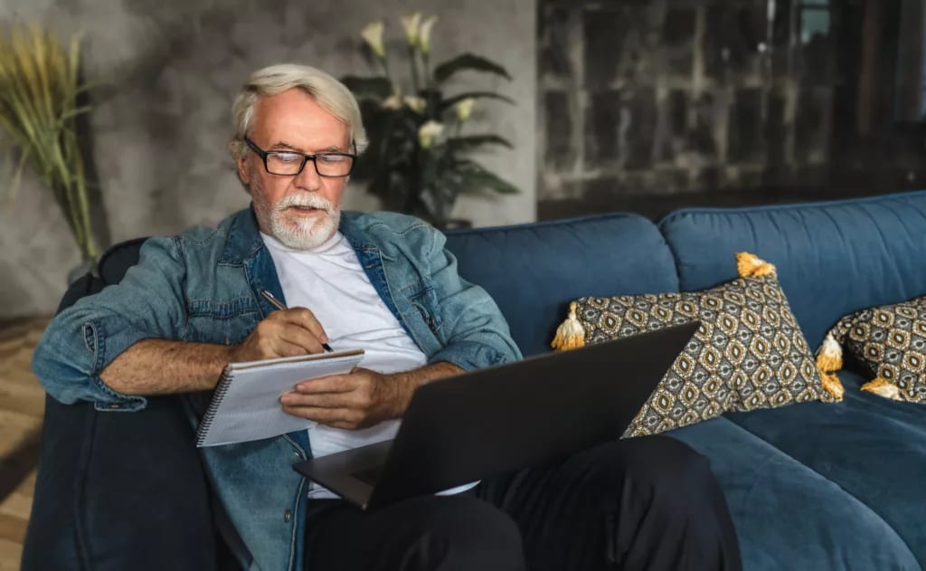 senior holding laptop and writing note in notebook.jpg