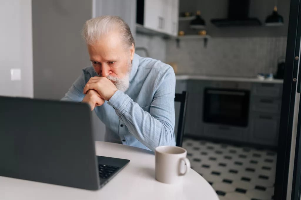 senior man laptop kitchen serious gettyimages .jpg