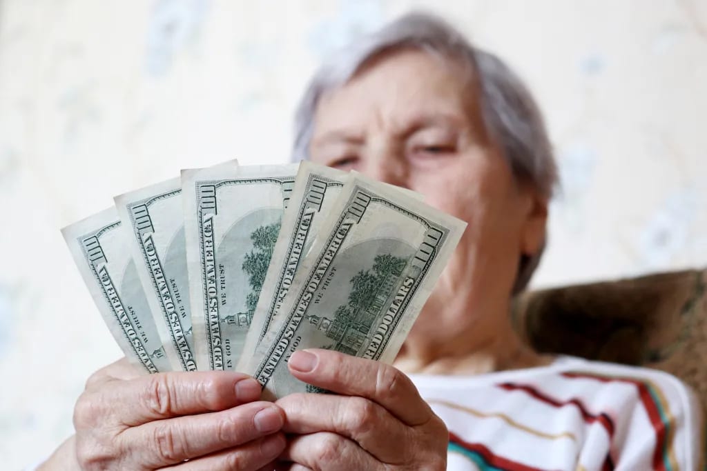 elderly woman retirement social security holding one hundred dollar bills cash getty.jpg