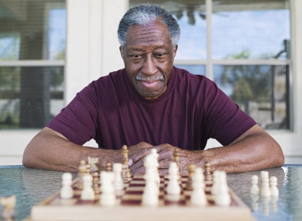 A person sitting in front of a chess board contemplating game strategy.