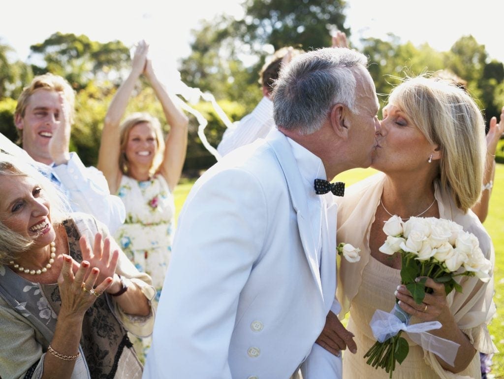 Group cheering on kissing couple at wedding.