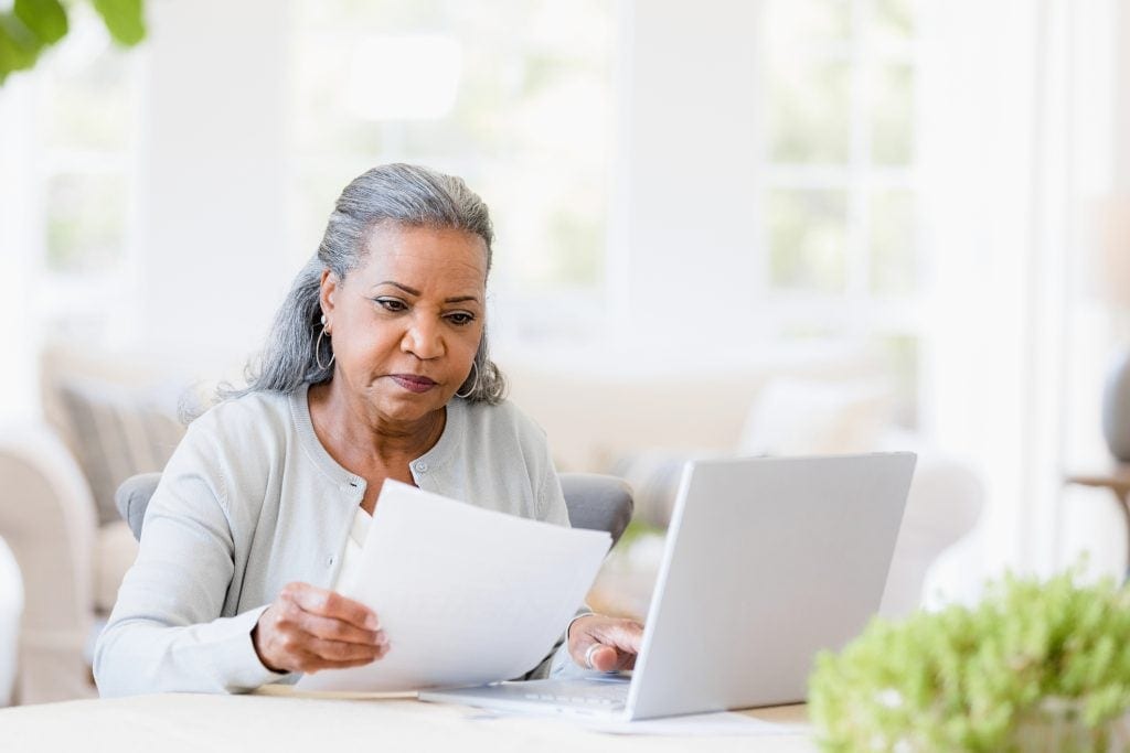 A person at a laptop looking at a document.