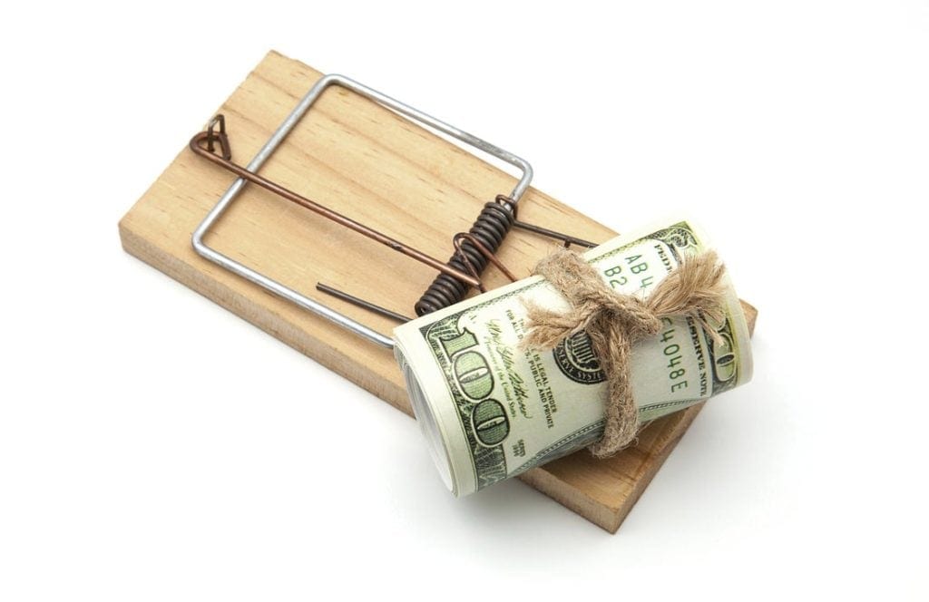 A mouse trap with a roll of $100 bills sitting on top.