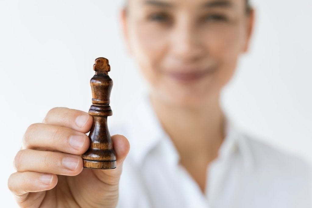 A person holding up a king chess piece.