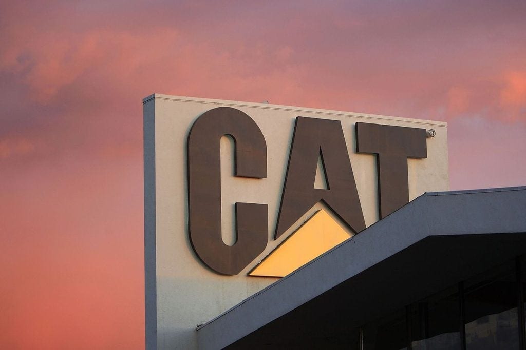 CAT logo on a building against a pink sunset sky.