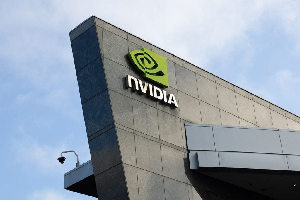 Nvidia logo mounted on the exterior of a modern office building under a cloudy sky.