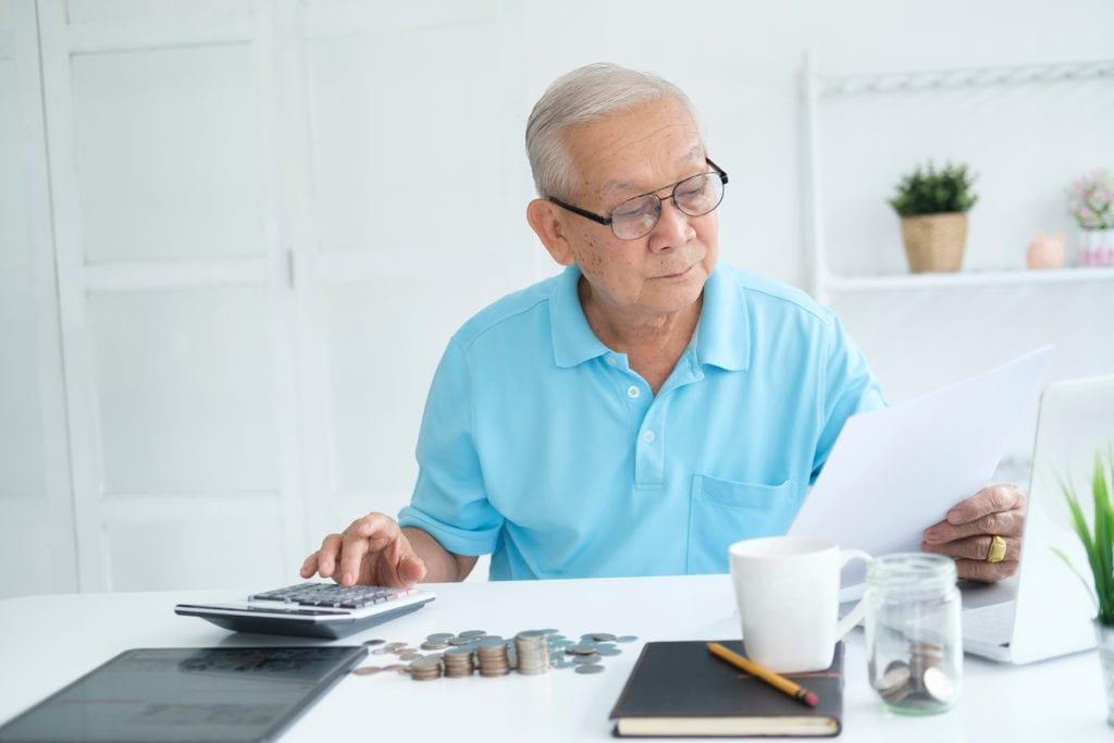 Person holding document and typing on calculator.