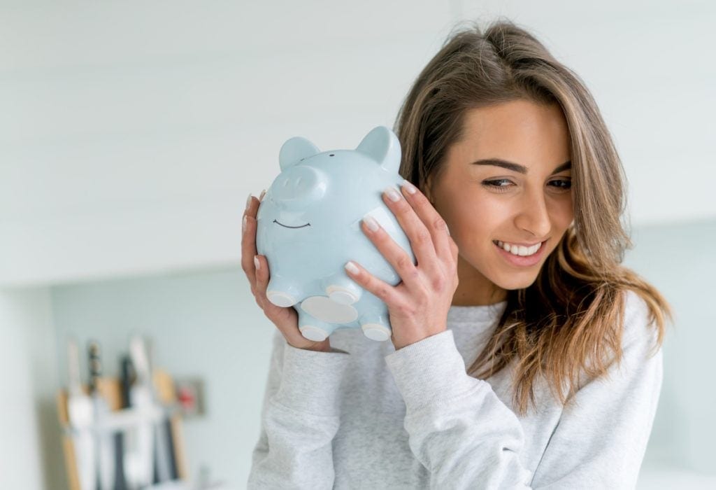 Smiling person shaking piggy bank.