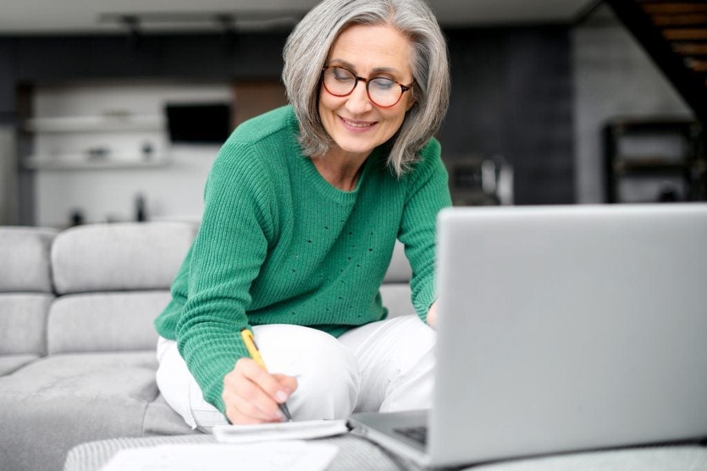 Smiling person writing note in notebook.