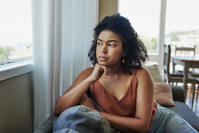 young person with a worried expression looking out a window