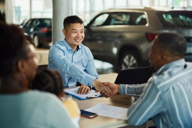 Salesman and customer shaking hands over pape.width .jpg