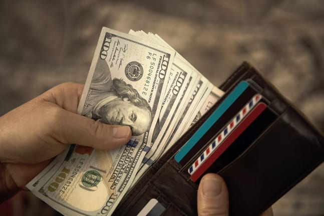 person placing hundred dollar bills into a wallet.jpg