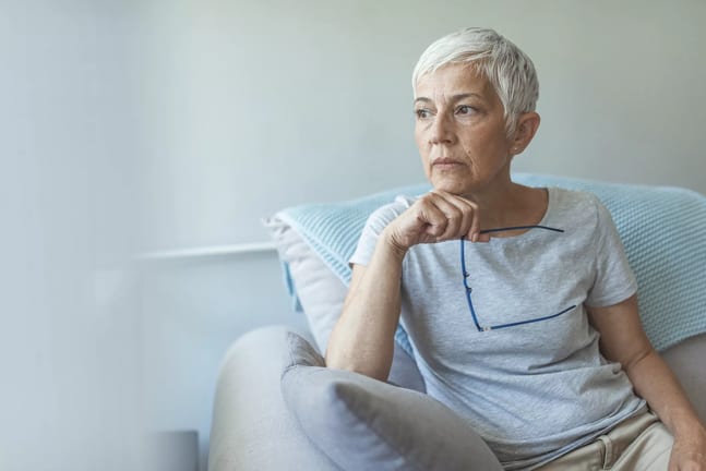 person sitting in a chair holding eyeglasses.jpg
