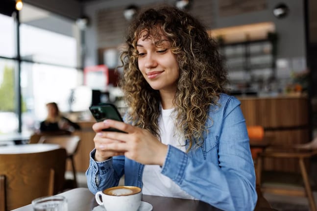 smiling person looking at smartphone in coffee shop.jpg