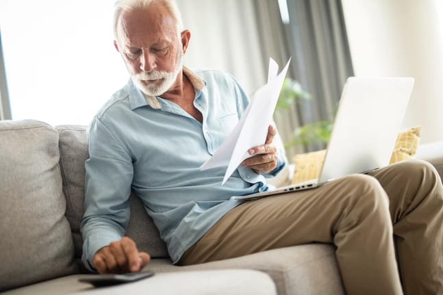 senior man couch docs calc laptop gettyimages .jpg