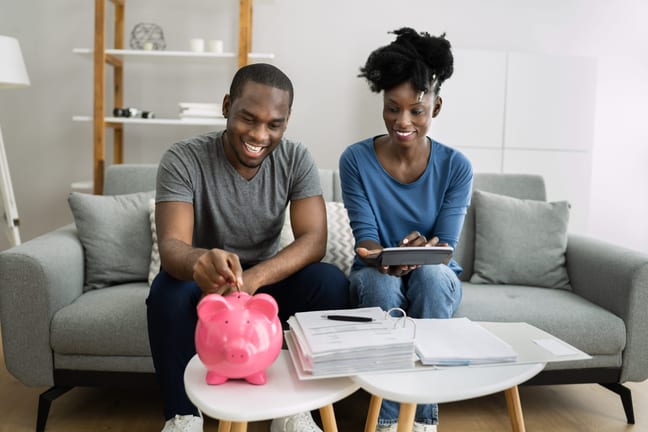 couple putting money in a piggy bank gettyimages JHHjH