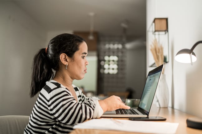person sitting at desk and typing on laptop