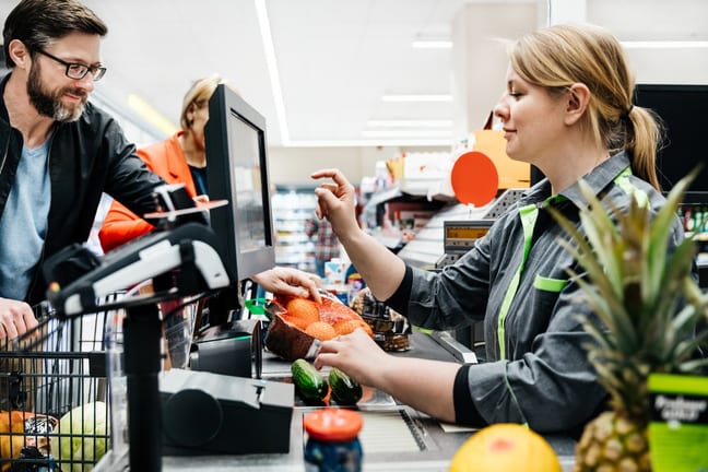 Grocery store employee ringing up customers .width