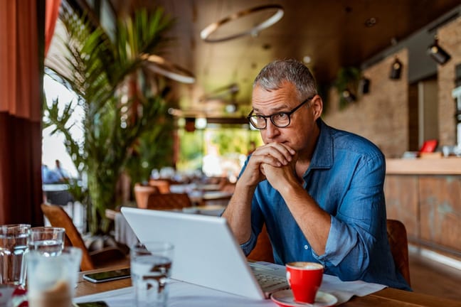 Man sits at laptop and appears to be in thoug.width TzgSuj