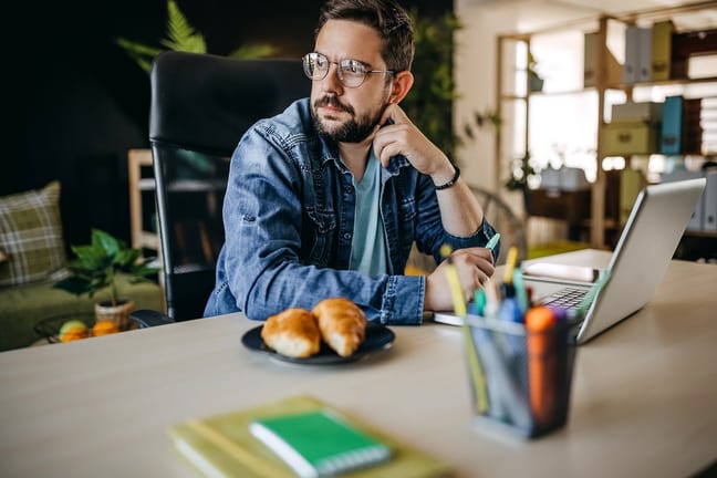 Man using laptop looks away appearing to be i.width mpyFQA
