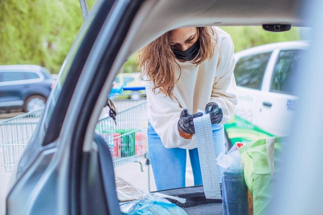 Woman loading car with groceries looks over h.width QbypC