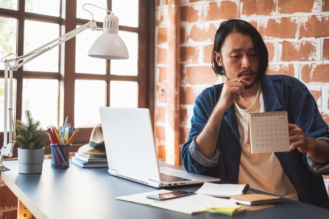 Young man pausing from using his laptop to lo.width GUCxw