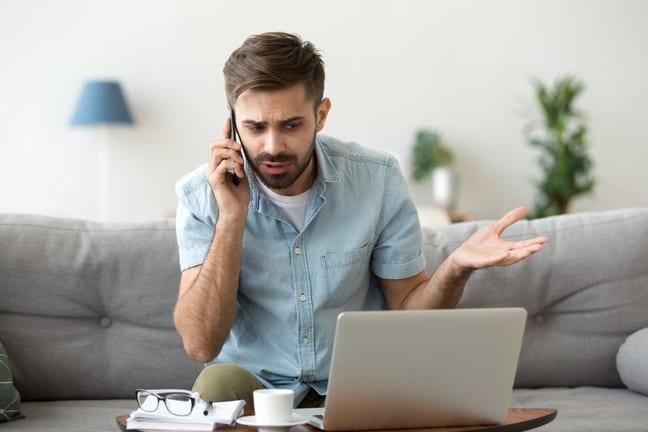 man on couch on phone call near laptop gfF.width .jpg