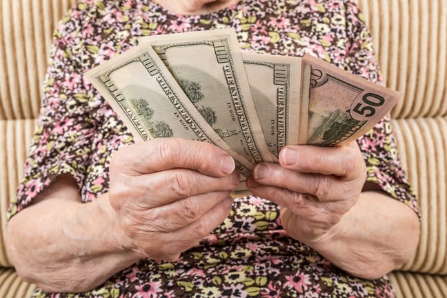 senior woman holding cash money bills social security cola retirement getty