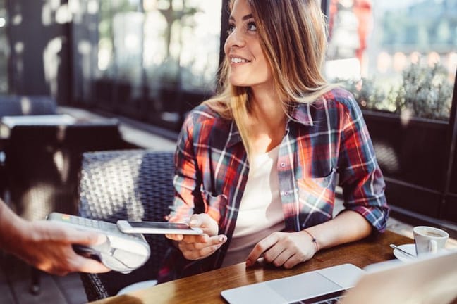 woman in restaurant paying with smart phone a.width