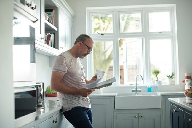 worried man in kitchen with bills fEoJV.width