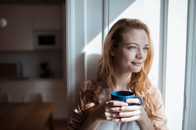 smiling person sitting in window holding coffee mug.jpg