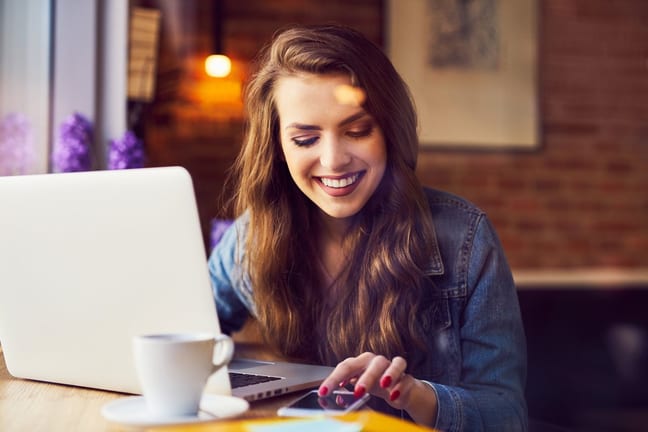woman smiling with coffee and computer vkYiv.width .jpg