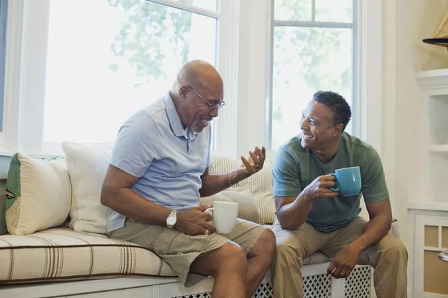 Cheerful father and son having coffee on sofa.width .jpg