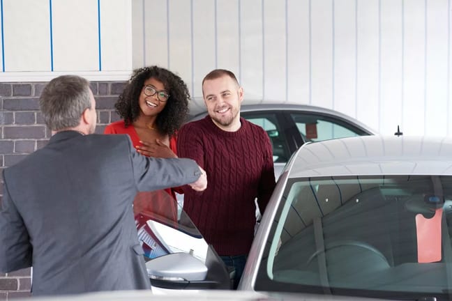 Couple shakes hand with a car salesman near a.width DnSBi.jpg