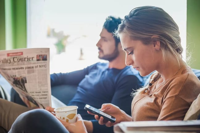 Couple sits together while one reads a newspa.width HSHgLW.jpg