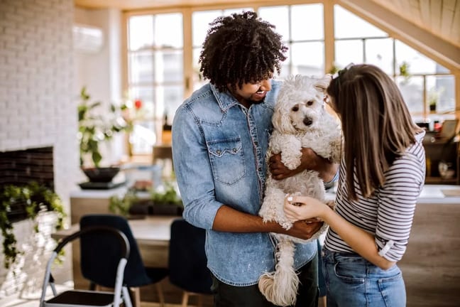 Millennial couple holding dog inside home io.width .jpg