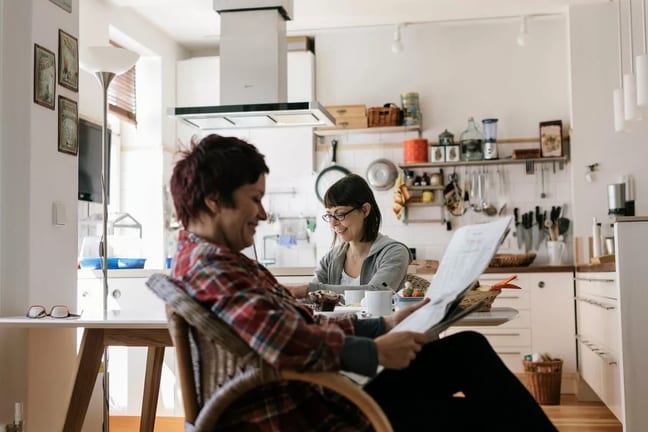Two people in a kitchen reading the news toJ.width .jpg