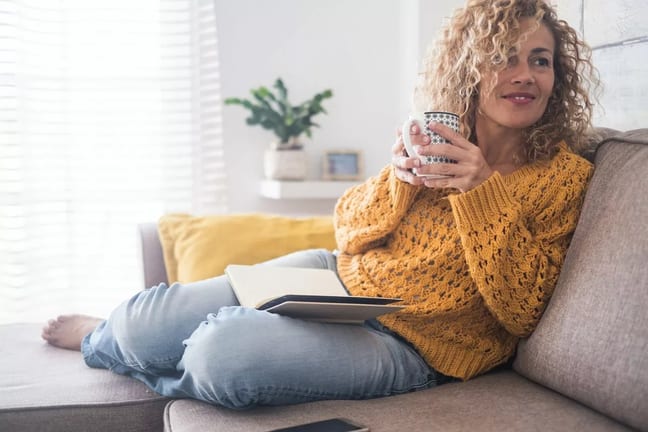 Woman drinking coffee on couch GTFVC.width .jpg