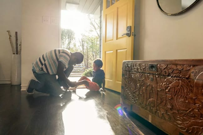 person putting on childs shoes at front door .width hxnClq.jpg