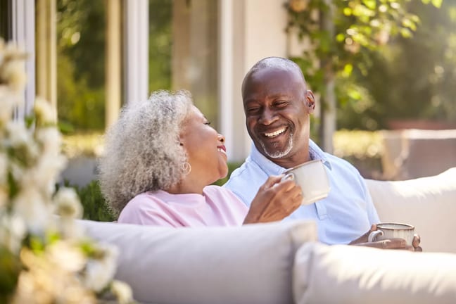 two older people sitting outside drinking coffee and smiling.jpg