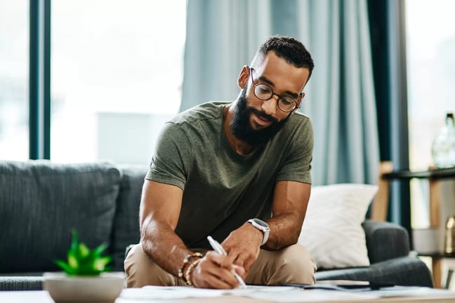 younger man sitting on a couch writing.jpg