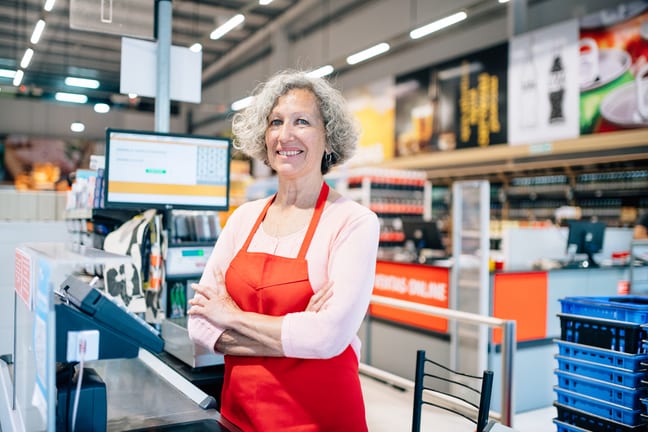 a smiling person in an apron at a register gettyimages .jpg