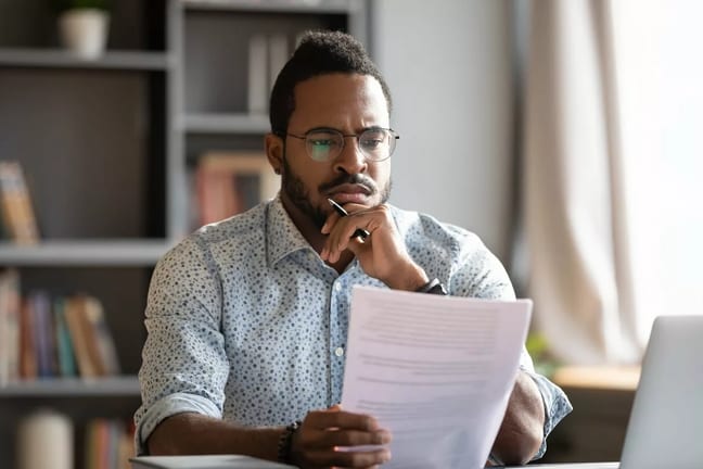 Man looking at documents with unsure expressi.width JzQldPC.jpg