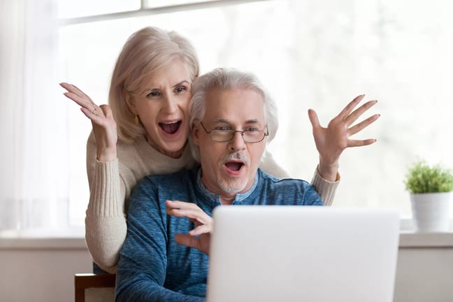 getty couple looking at laptop and exclaiming in happiness happy surprised thrilled.jpg