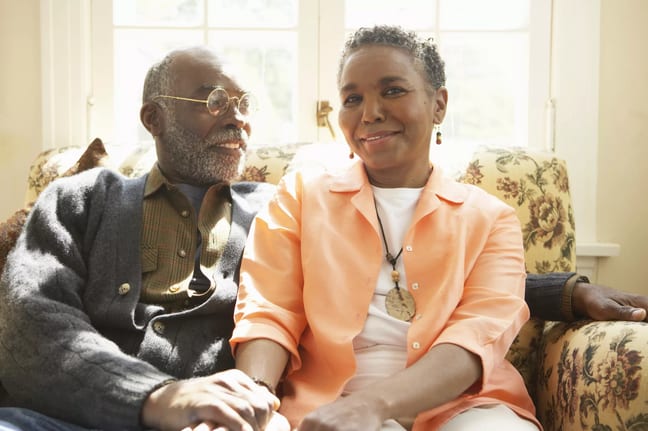 two older people sitting on a couch holding hands.jpg