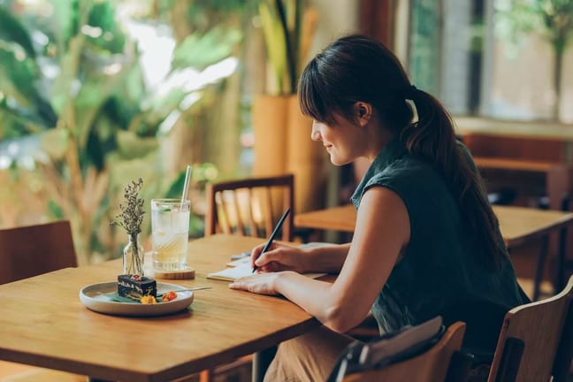Woman writes letter at cafe table YKfcOac.width .jpg