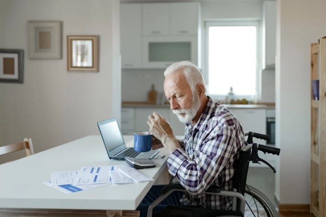 man in wheelchair at desk with financial stuff.jpg