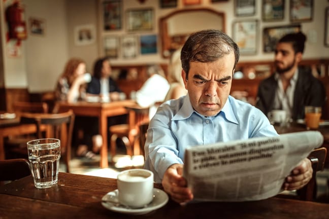 man with dwarfism reading newspaper at cafe.jpg