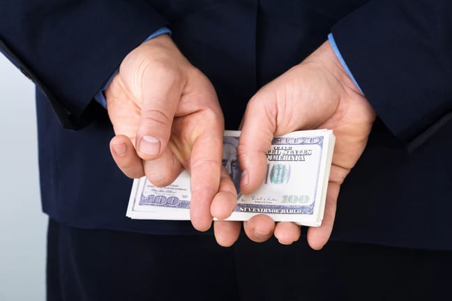 money behind back fingers crossed corporate tax getty.jpg