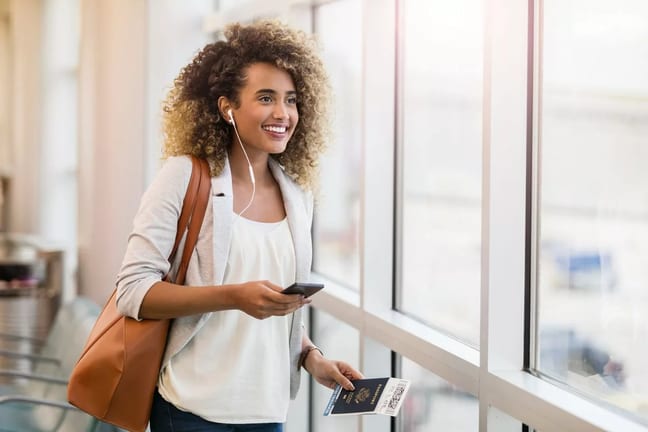 woman smiling in airport with suitcase and pa.width zsxbQ.jpg